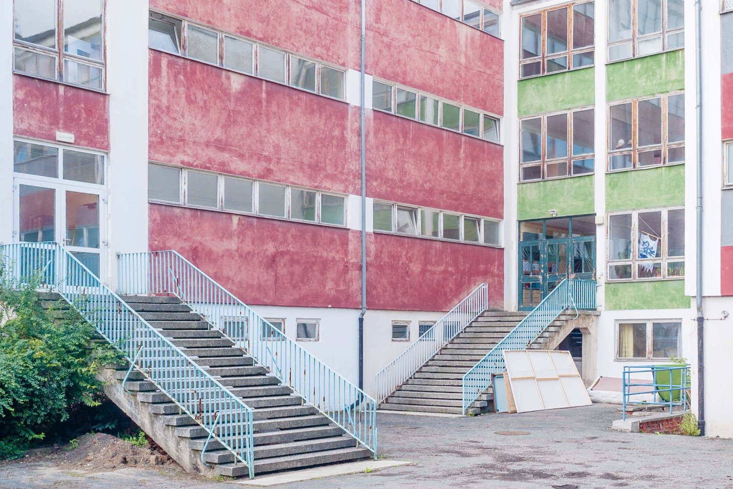 Eingangssituation des ehemaligen Schulgebäudes. Treppen führen zu den Eingängen.