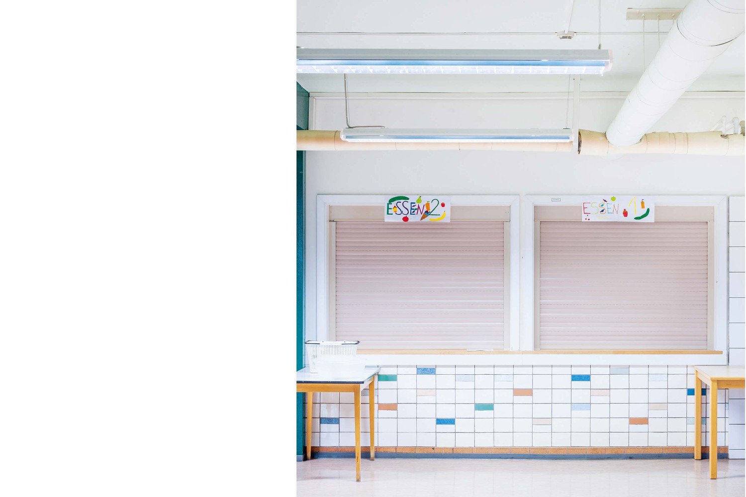 Die beiden Ausgabefenster der Küchentheke im ehemaligen Schulgebäude mit geschlossenen Rolläden.