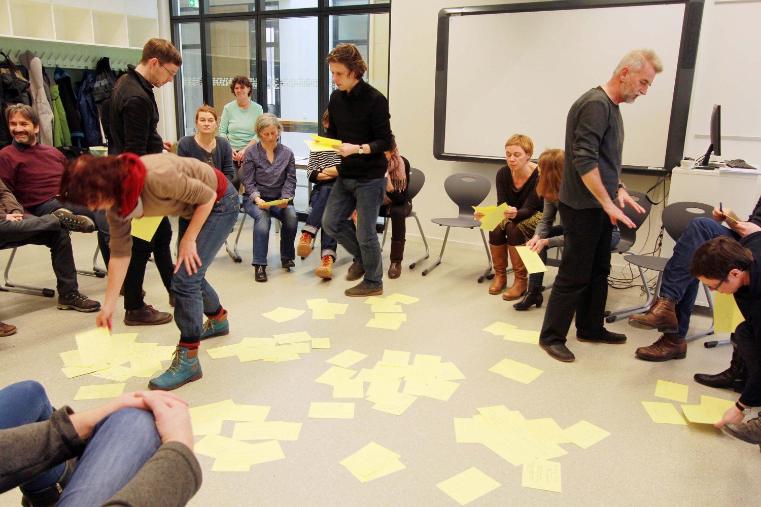 Sitzkreis der Beteiligten im Phase Null Prozess. Gelbe Zettel liegen auf dem Boden. In der Mitte des Kreises sind Tobias Haag und Walter Heilmann zu sehen.